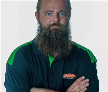 Man with beard in SERVPRO uniform posing for a picture on a white background