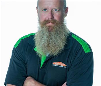 Man with a beard in SERVPRO uniform posing for a picture on a white background