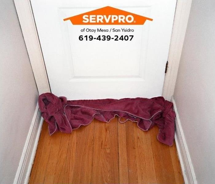 A towel blocks water from entering a room during a water damage emergency.