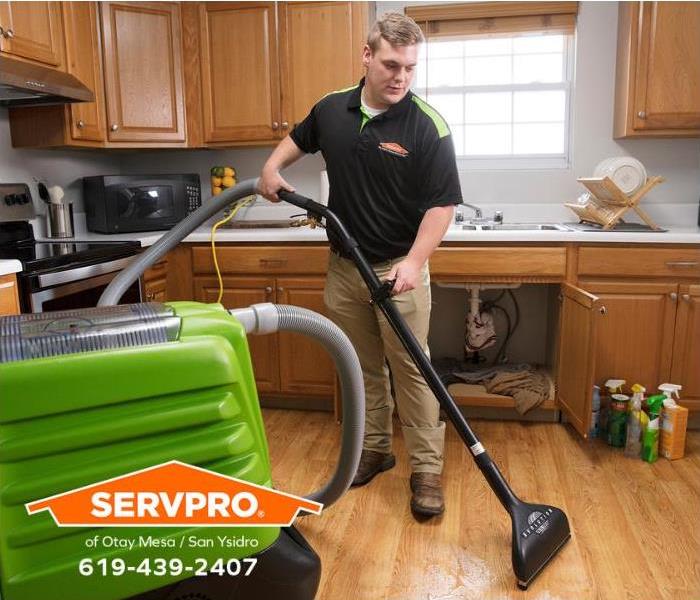 A SERVPRO technician is extracting water from a flooded kitchen floor. 